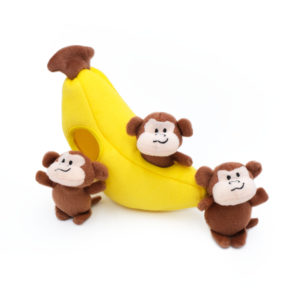 Three small, plush monkey toys are placed around and inside a larger Zippy Burrow® - Monkey 'n Banana with a hole in it.