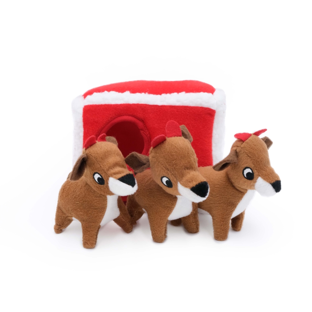 Three brown Holiday Burrow® - Reindeer Pen are in front of a red and white plush house.