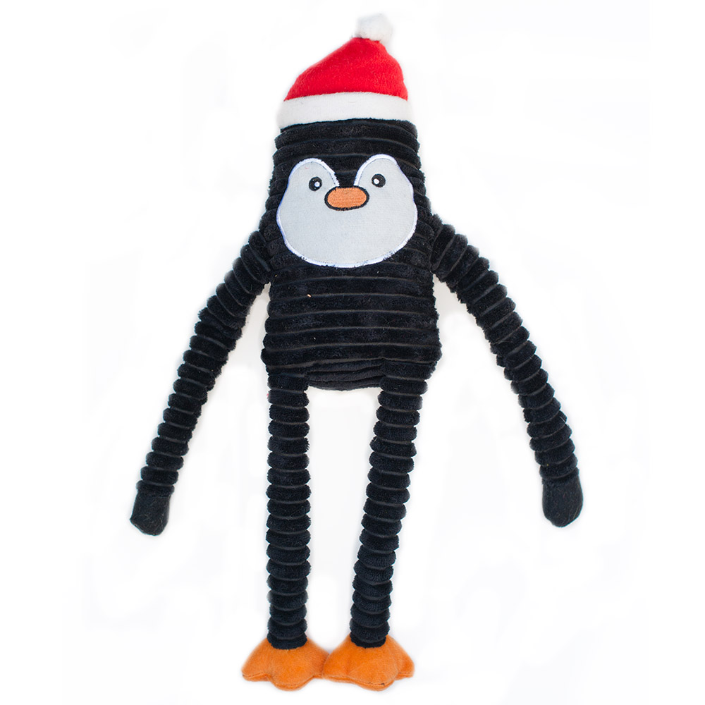 Stuffed toy penguin with black ribbed body, white face, orange beak and feet, wearing a red Santa hat against a white background.
