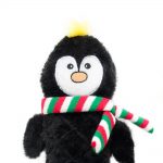 A black plush penguin toy with a yellow tuft of hair wearing a red, white, and green striped scarf.