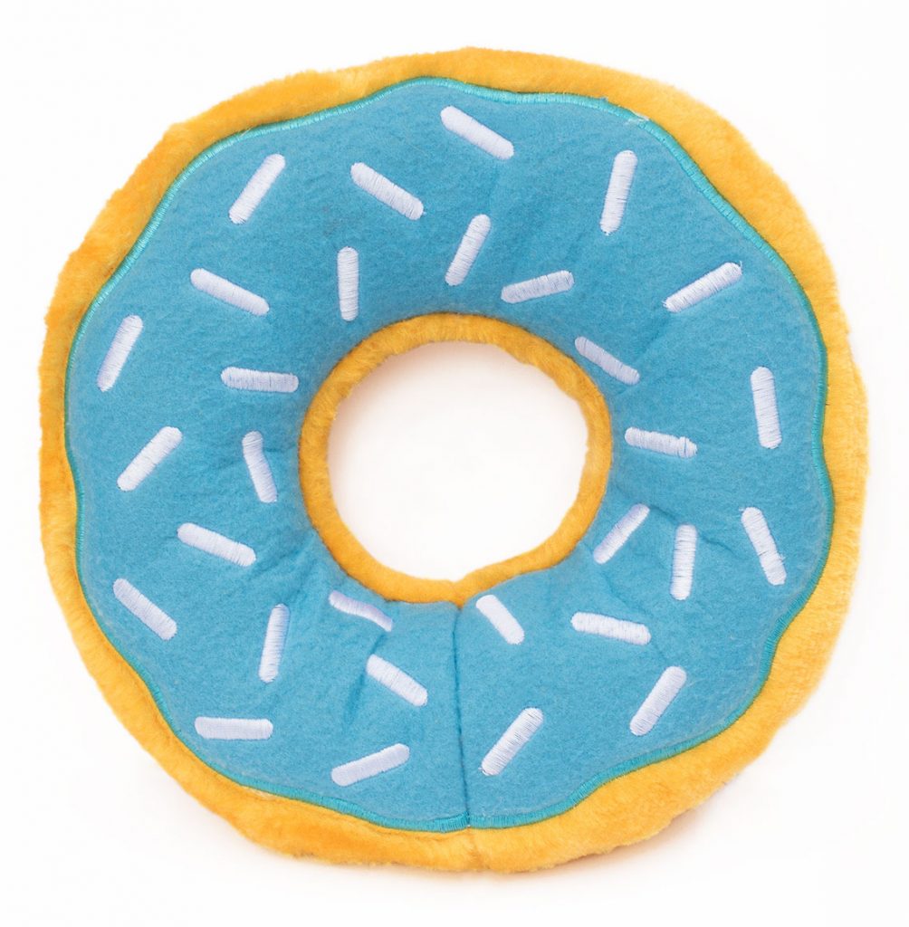 A round plush toy resembling a donut with a blue top decorated with white sprinkles and a yellow base.