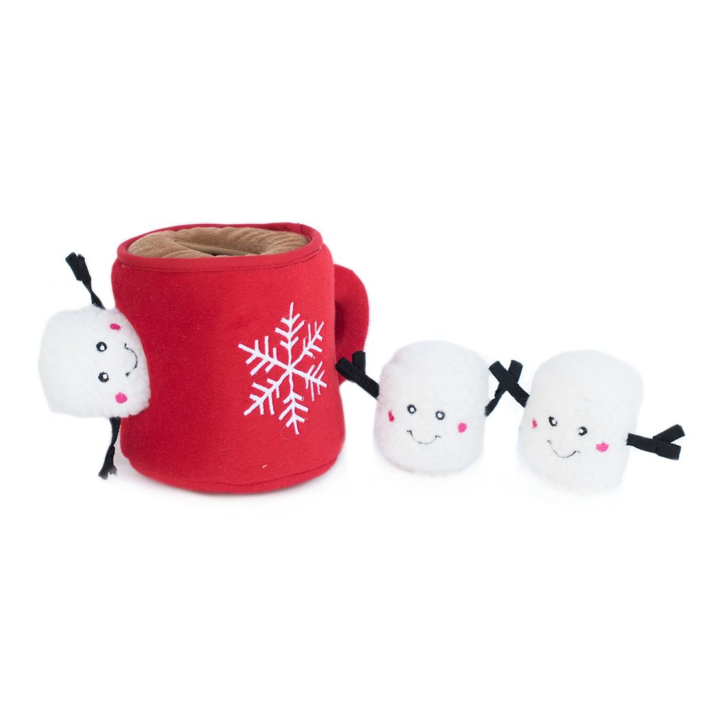 A plush red mug with a white snowflake design on the front. Three small plush marshmallow toys with smiling faces are positioned around it.
