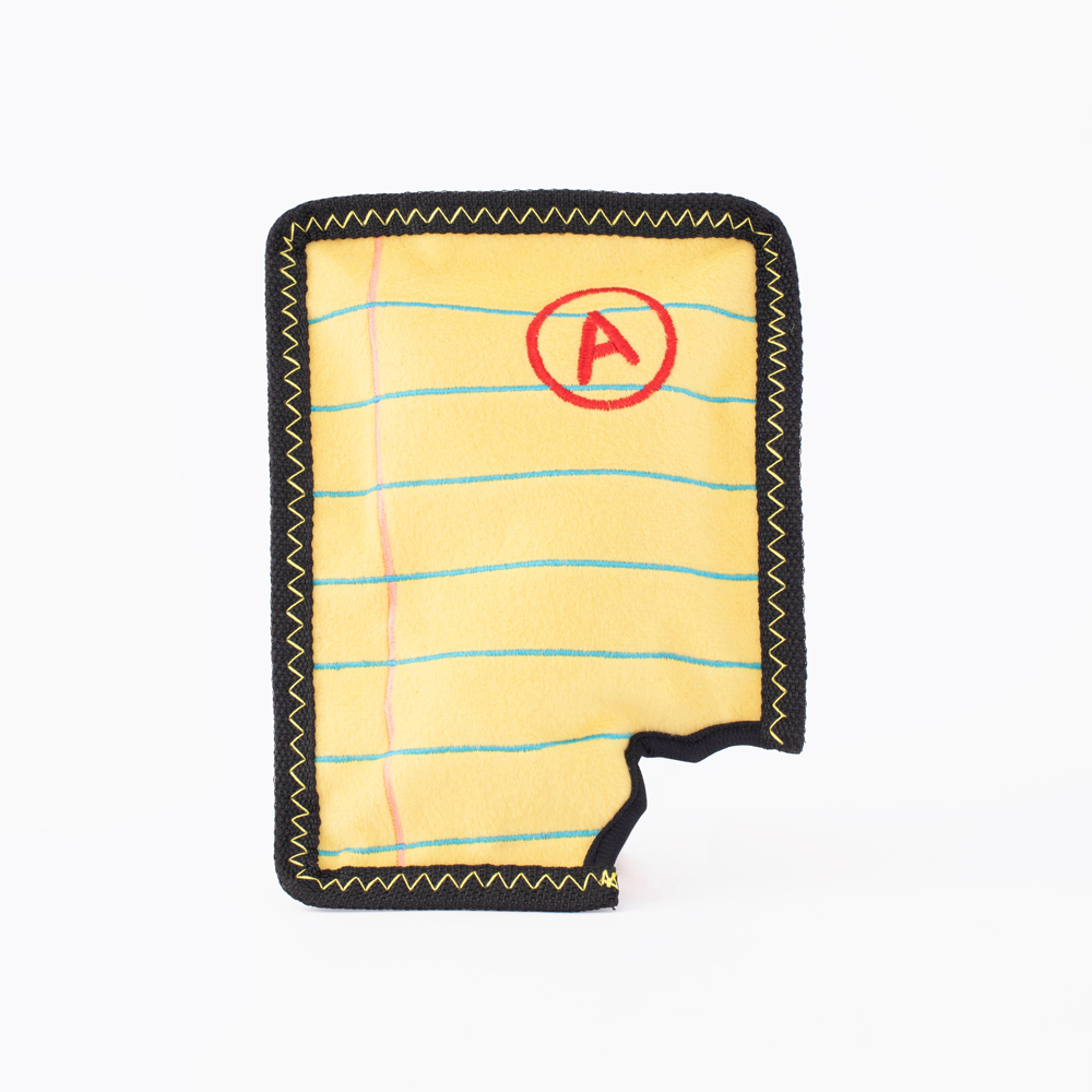 Photo of a yellow notebook page with blue lines and a red "A" grade. The shape is bordered by black stitching and has a bite-like cut on the bottom edge.