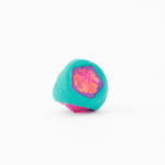 A small, multi-colored toy with teal, pink, and orange segments, featuring a textured exterior and geometric shapes.