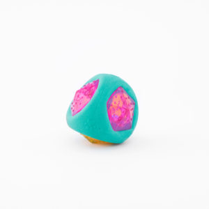 A teal and pink geometric toy with textured triangular indentations and a round shape, against a white background.
