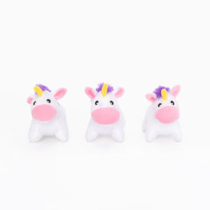 Three small, white unicorn plush toys with pink faces, purple manes, and yellow horns are arranged in a row against a white background.