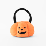 A small, orange, pumpkin-shaped fabric basket with a smiling jack-o'-lantern face and a black handle, isolated on a white background.