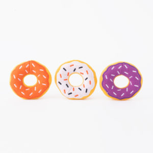 Three colorful toy donuts with sprinkles are arranged in a row against a white background. The donuts are orange, white, and purple.