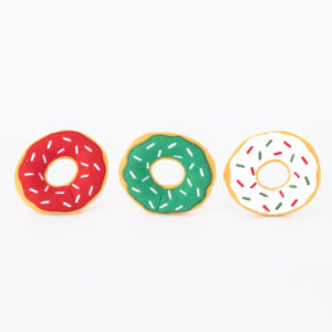 Three plush toy donuts are displayed in a row against a white background. The donuts are red with white sprinkles, green with white sprinkles, and white with red and green sprinkles.