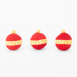 Three red and yellow striped plush balls are arranged in a row against a plain white background.