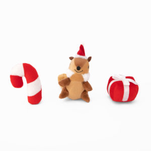 Three plush holiday toys: a red and white candy cane, a brown chipmunk wearing a red Santa hat, and a red gift box with a white ribbon.