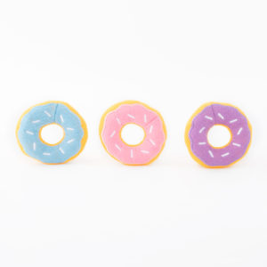 Three plush toy donuts with icing in blue, pink, and purple, each decorated with white sprinkles, are arranged in a row against a white background.