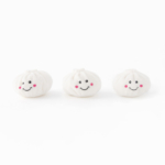 Three small, white steam buns with smiling faces and rosy cheeks are lined up in a row against a white background.