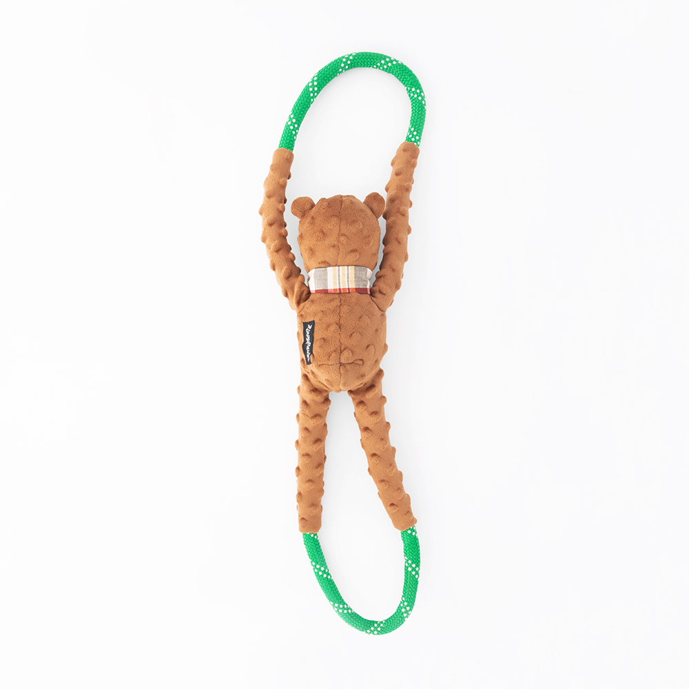 A brown plush monkey toy with outstretched arms and legs is attached to a green, polka-dotted loop, forming a stretchy ring.