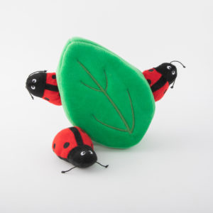 A plush green leaf toy with three plush red and black ladybugs attached to it.