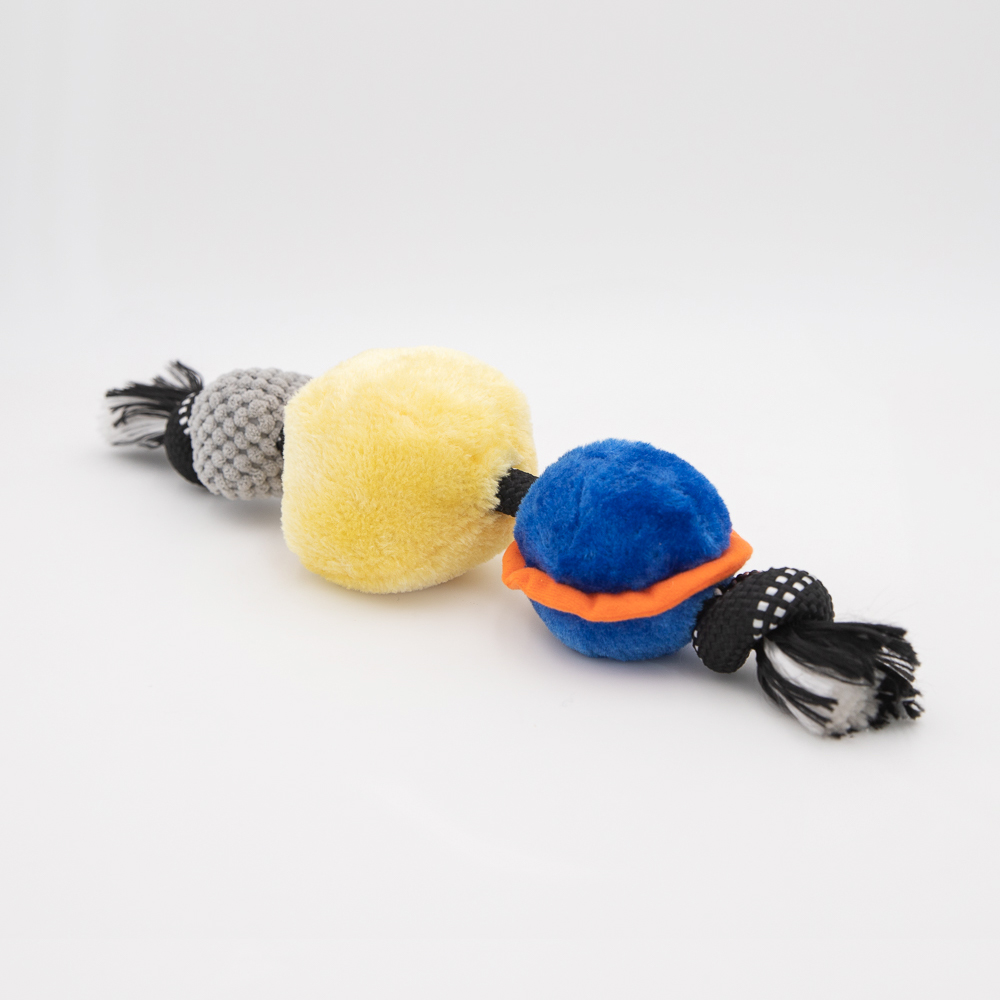 A colorful dog toy consisting of three plush balls in yellow, gray, and blue, connected by a black-and-white braided rope.