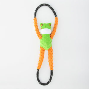 A green and orange frog-shaped dog toy with two loop handles, one above its head and one below its feet.