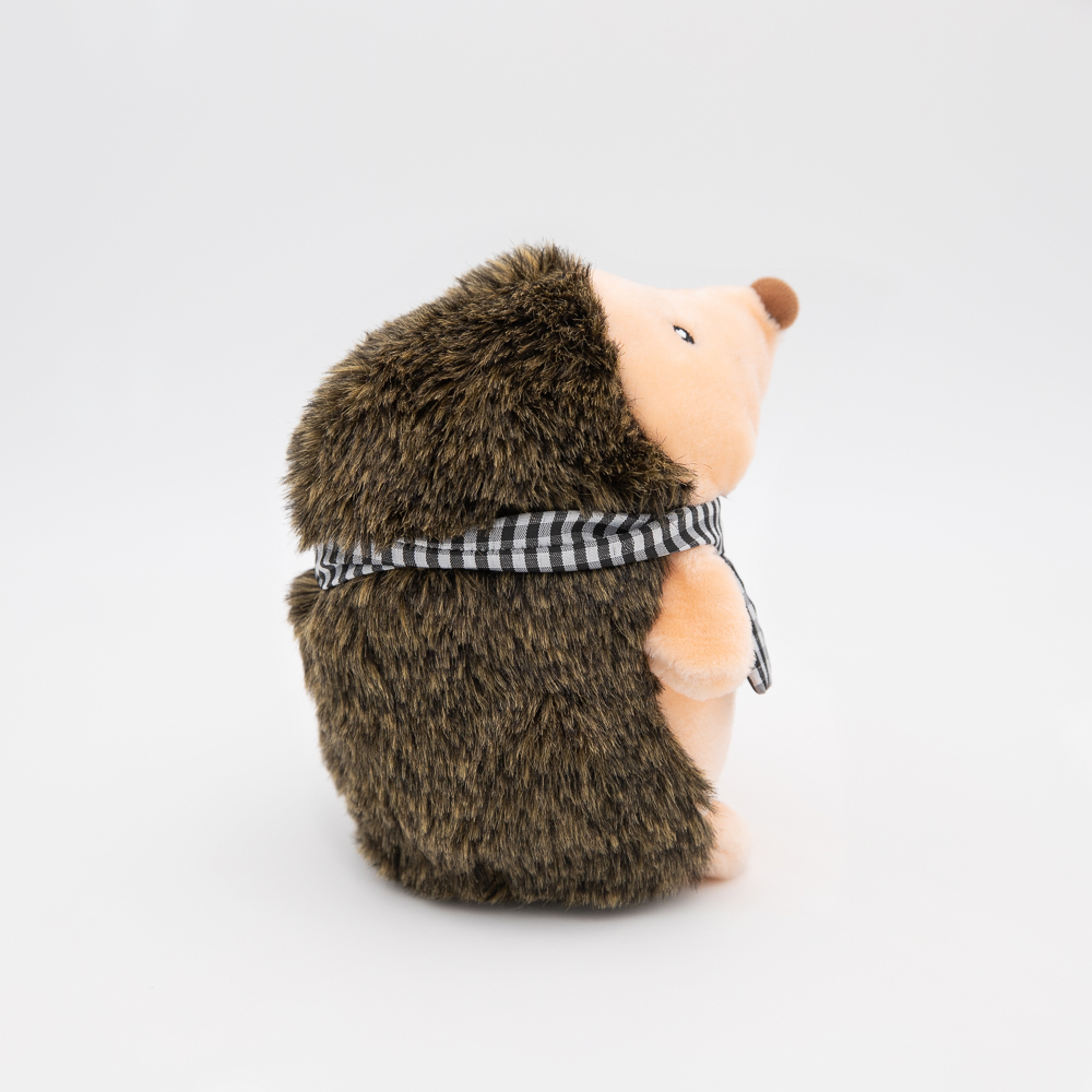 A plush toy hedgehog wearing a black and white checkered scarf, viewed from the side against a plain white background.