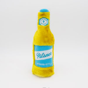 A plush toy shaped like a yellow and blue pilsner beer bottle labeled "Pilsner" and "German-Style".