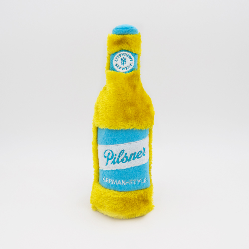 A plush toy shaped like a yellow and blue pilsner beer bottle labeled 
