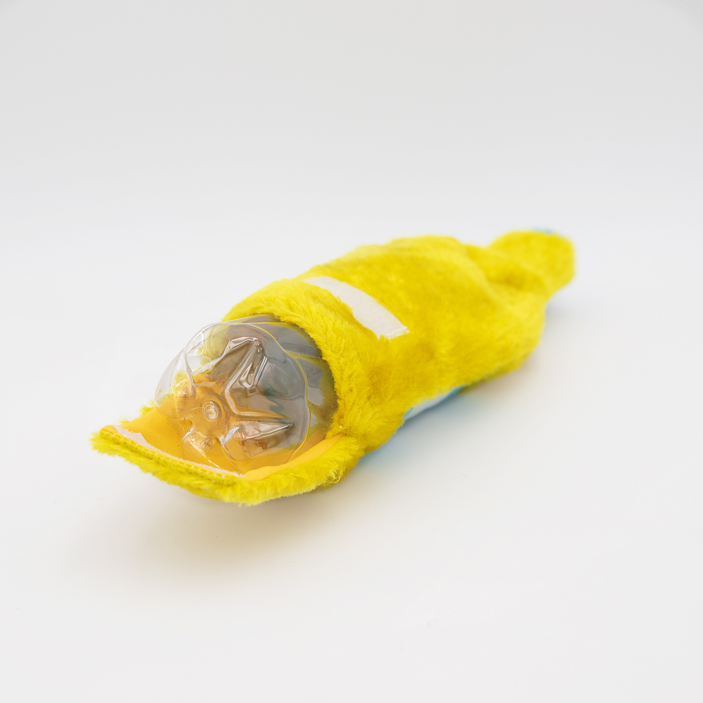 A yellow plush dog toy lies on its side with a clear plastic ball inside, against a white background.