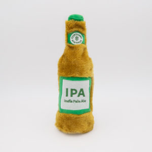 A plush toy shaped like a beer bottle with a brown body, green cap, and a green label reading "IPA India Pale Ale.