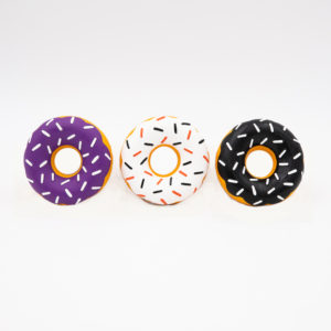 Three inflatable donut-shaped pool floats with icing designs in purple, white, and black, each featuring colorful sprinkles, arranged in a row against a plain background.