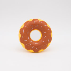 A toy donut with a yellow base, brown frosting, and white sprinkles is placed against a plain white background.