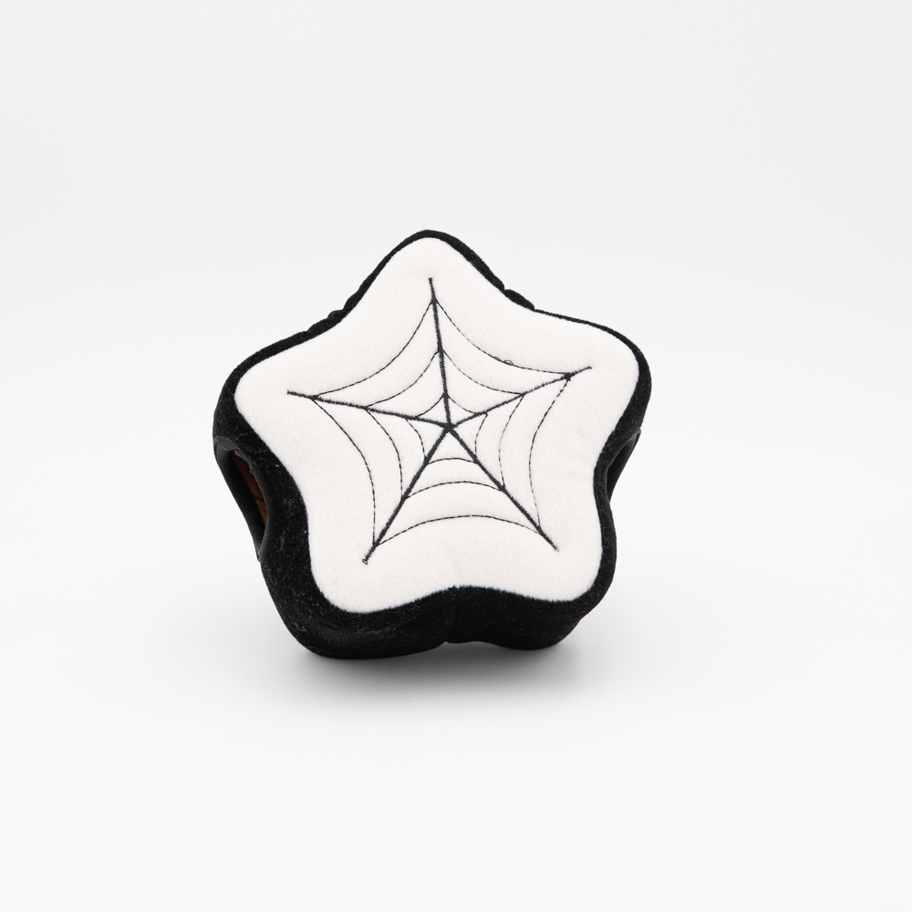 A black and white star-shaped plush toy with a spider web design embroidered on the front.