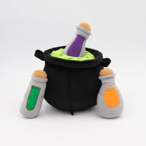 Plush toys depicting a black cauldron with green liquid and three potion bottles colored green, purple, and orange arranged around it.