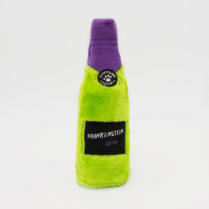 A plush toy bottle with a green body, black label, and purple cap. The label reads "Frankenstein Wine." There's a black circular tag with a paw print at the top.
