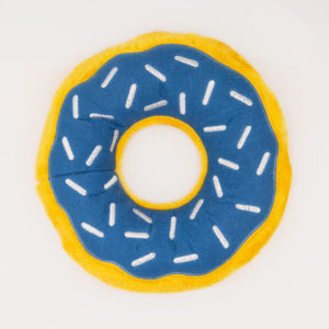 A round, plush toy shaped like a donut with blue fabric, white sprinkles, and a yellow outer edge.