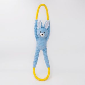 A plush blue rabbit toy with long limbs is attached to a yellow oval-shaped ring. The background is plain white.
