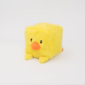 A small, plush yellow square toy with an orange beak and simple black eyes, resembling a chick, against a plain white background.