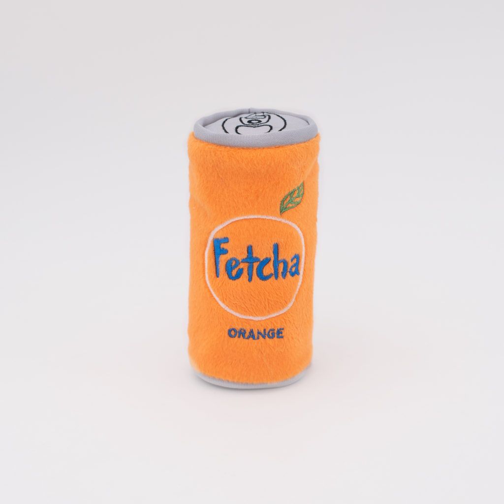 An orange cylindrical plush toy designed to resemble a soda can with the word 