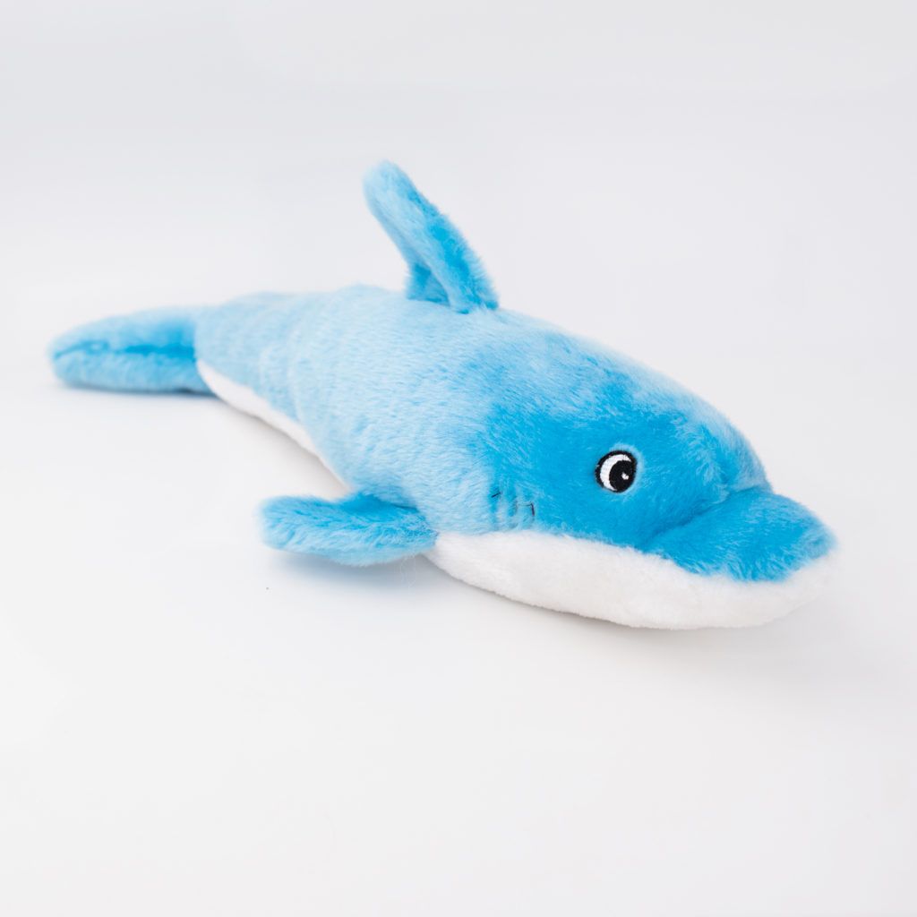 A soft, blue and white dolphin plush toy with a smiling expression lying flat on a white surface.