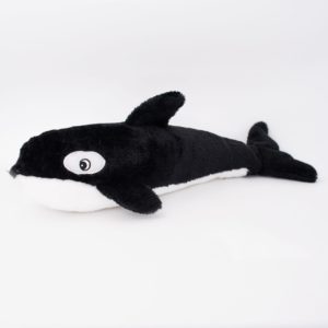 A black and white whale plush toy with large eyes is lying on a white background.