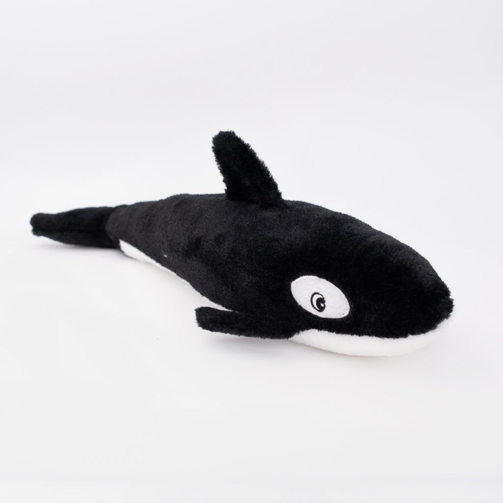 A black and white stuffed toy resembling an orca lies on a plain white background.