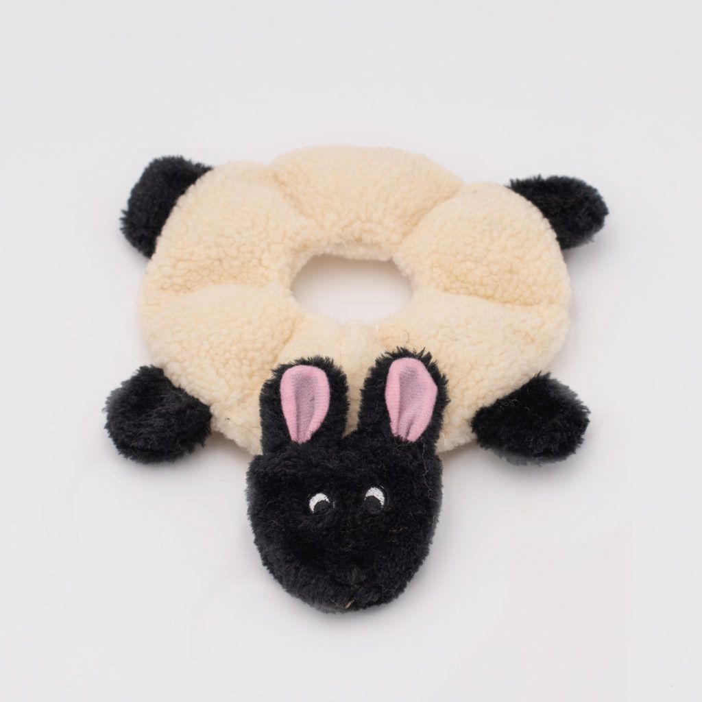 A round plush toy resembling a black sheep with four legs and floppy ears, positioned on a white background.