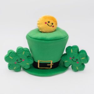 A green plush hat with a black buckle, accompanied by two plush shamrocks and a plush yellow coin with smiling faces.