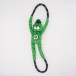 A green, plush bear toy with a cloverleaf on its belly and wearing a small hat is attached to a looped black and white rope, set against a plain white background.