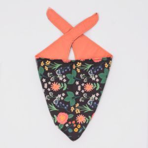 A Bandana - Black Floral with a black background and coral reverse side, laid flat on a white background.
