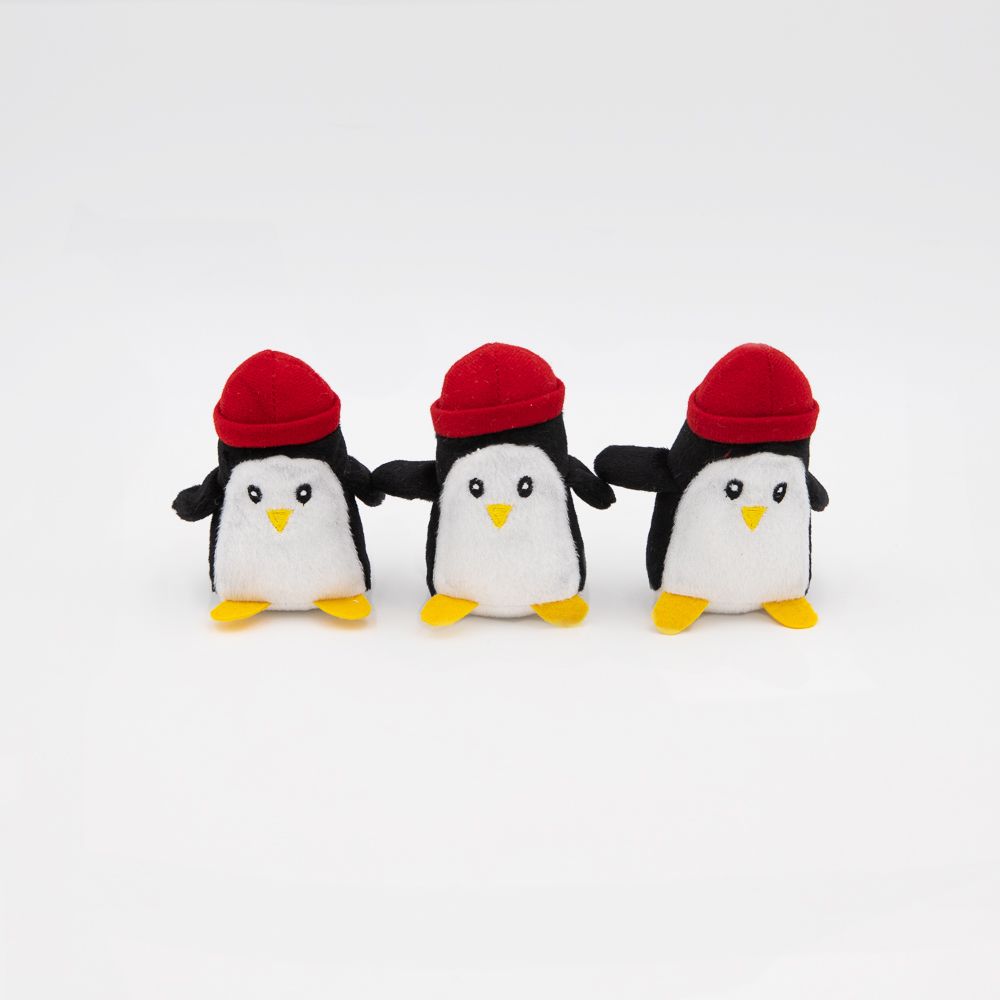 Three plush penguin toys wearing red hats stand in a row on a white background.