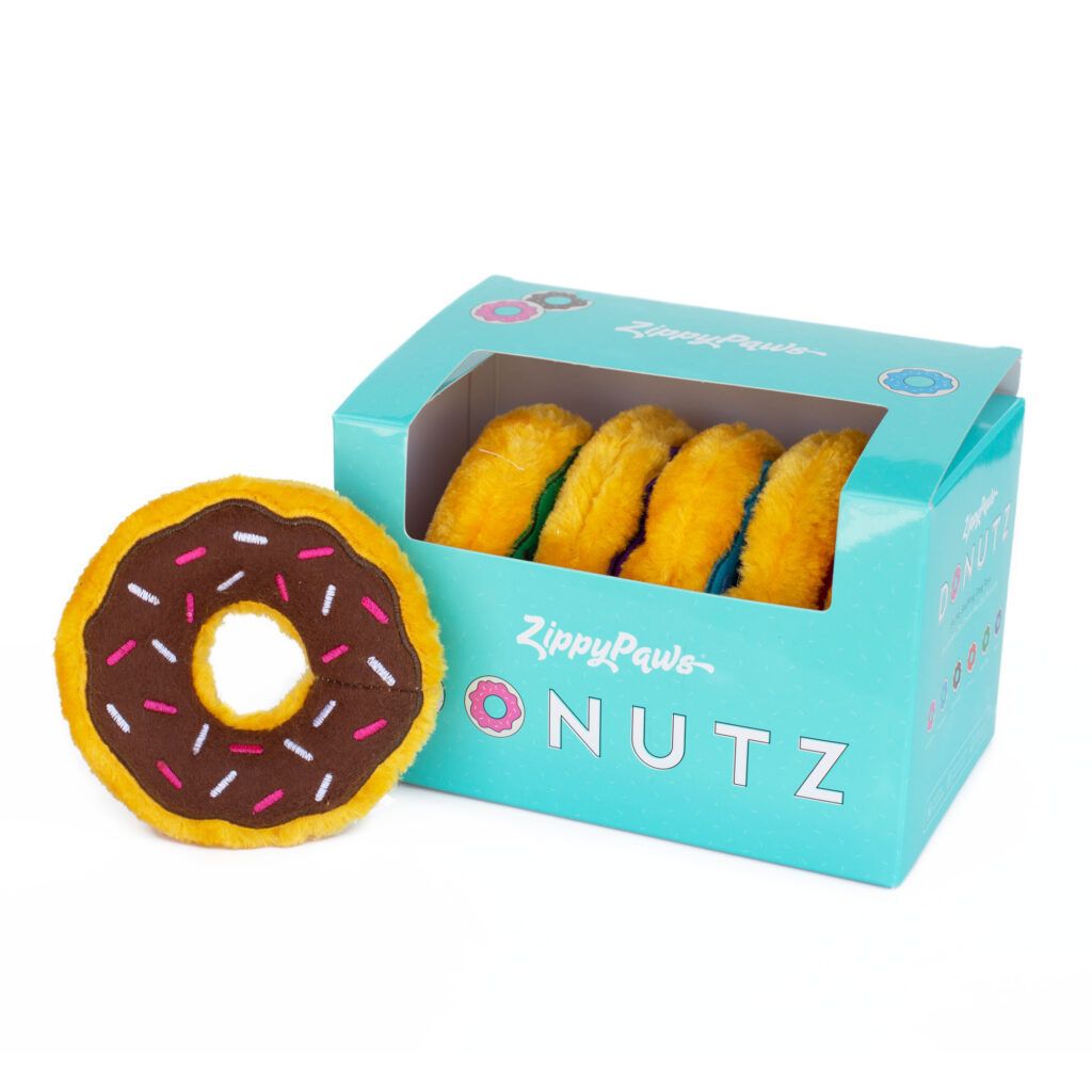 A box labeled "ZippyPaws Donutz" containing several plush donut toys with colorful sprinkles. One plush donut is placed beside the box.