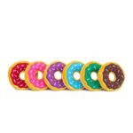 A row of six plush donuts with colorful icing and sprinkles, arranged in red, pink, purple, blue, green, and brown from left to right.