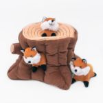 Zippy Burrow® - Fox Stump featuring a brown tree stump with three detachable fox plushies, one on top and two peeking out from holes in the sides.