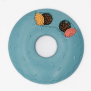 A blue, donut-shaped dog toy with compartments holding brown kibble and two chewable, yellow and pink treats. The toy is labeled "SmartyPaws Puzzler Donut Slider.