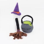 A Halloween Costume Kit - Witch featuring a purple witch hat with an orange band, a brown broom with a black handle, and a gray cauldron labeled "Witch's Brew" with a green interior and black handle.