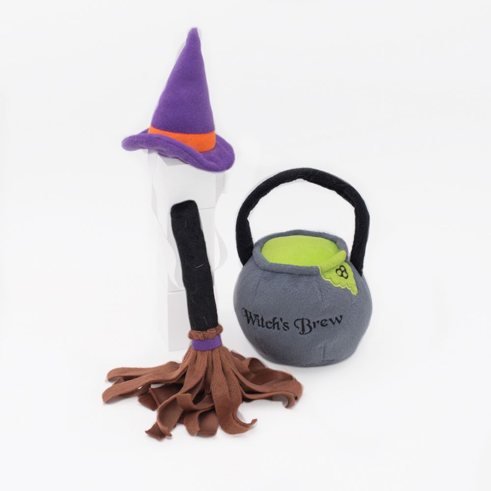 A Halloween Costume Kit - Witch featuring a purple witch hat with an orange band, a brown broom with a black handle, and a gray cauldron labeled "Witch's Brew" with a green interior and black handle.