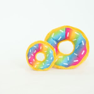 Two 2021 Donutz Release plush toy donuts with rainbow colors and white sprinkles, one smaller and one larger, are placed side by side against a white background.